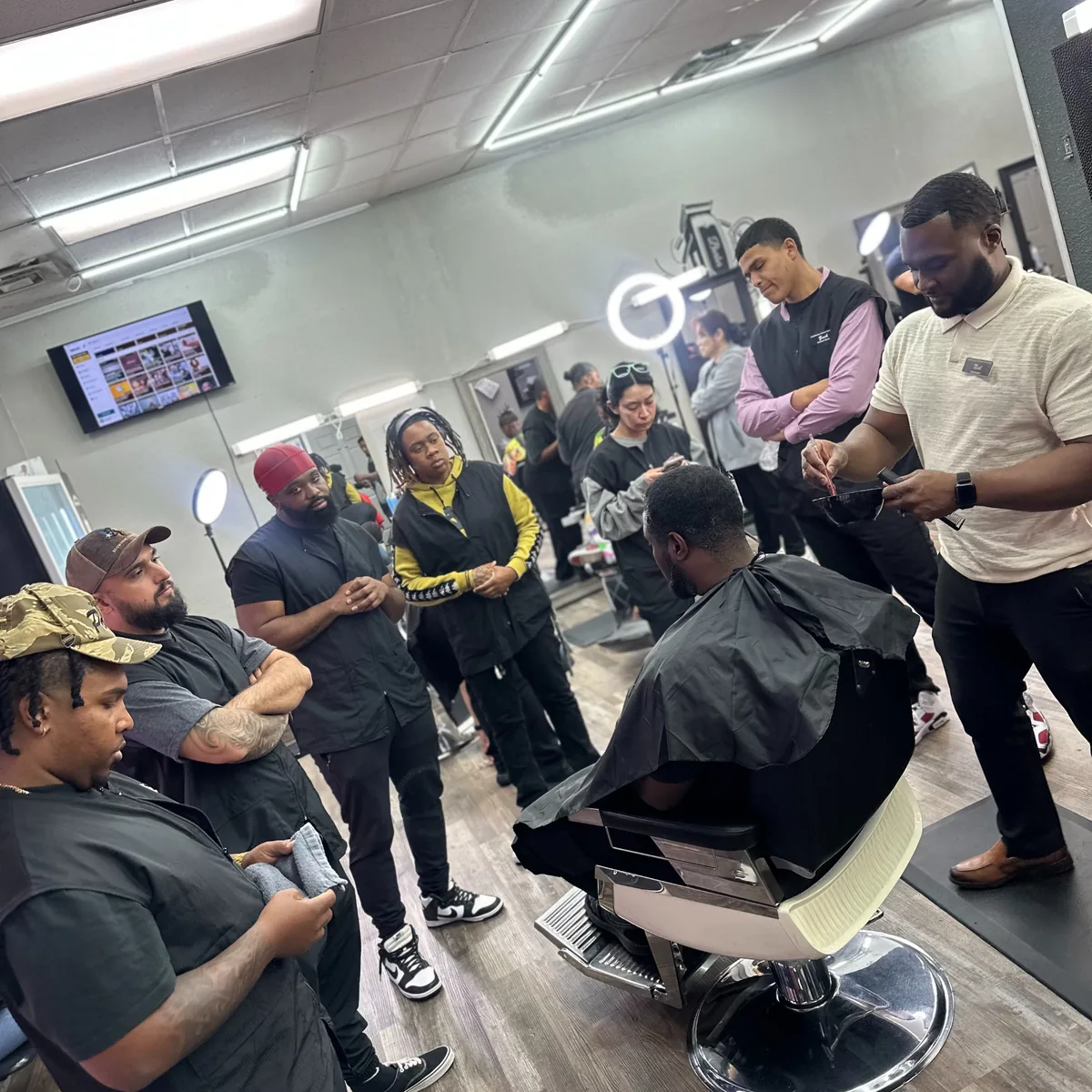The FadeMasterz floor: an instructor demonstrates on a client while the class gathers around the chair